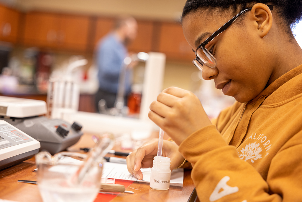 Student in a laboratory using equipment to do an experiment.