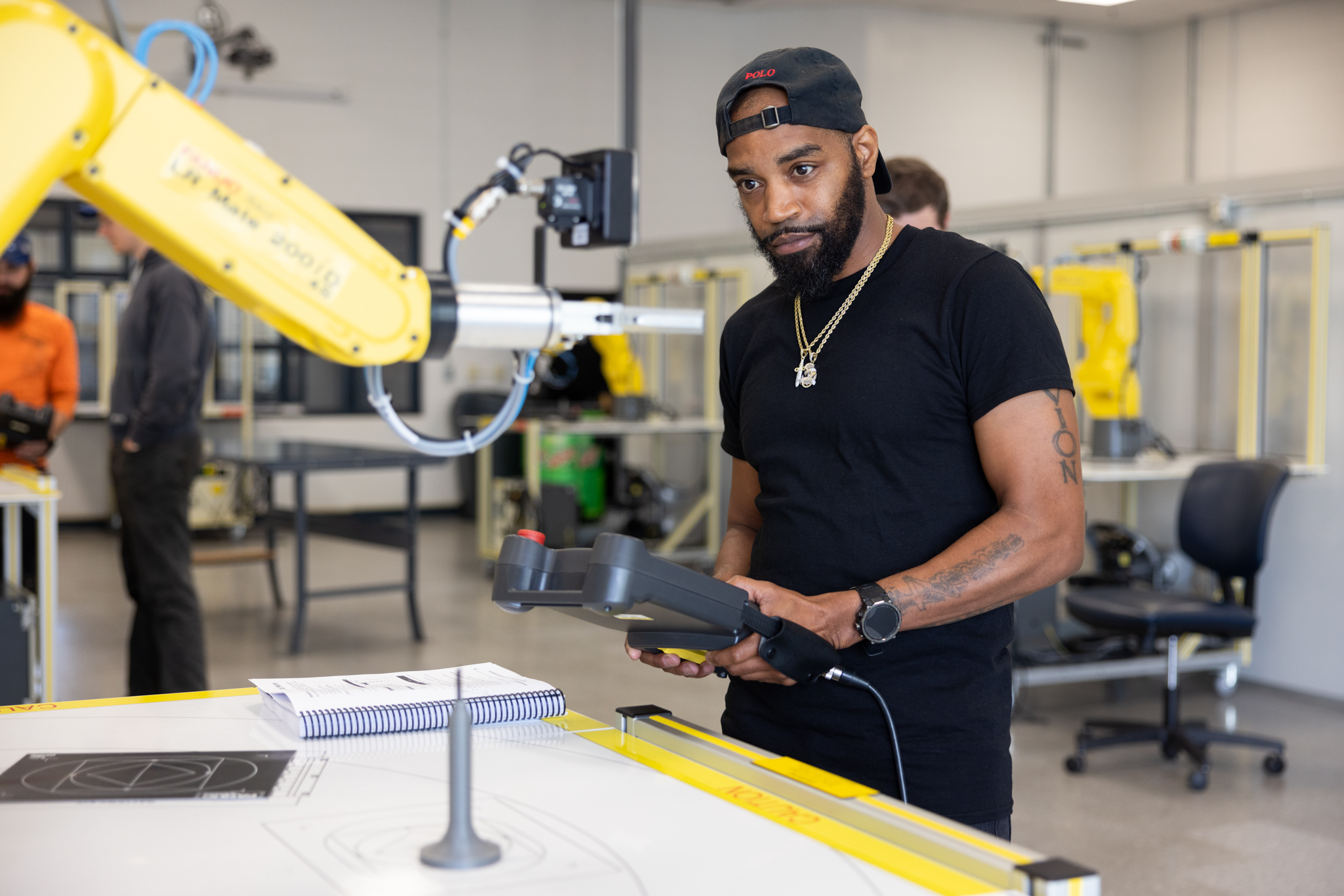 Workforce Solutions student enrolled in a FANUC course is learning how to use the controls to move a robotic manufacturing arm at Jackson State Community College.