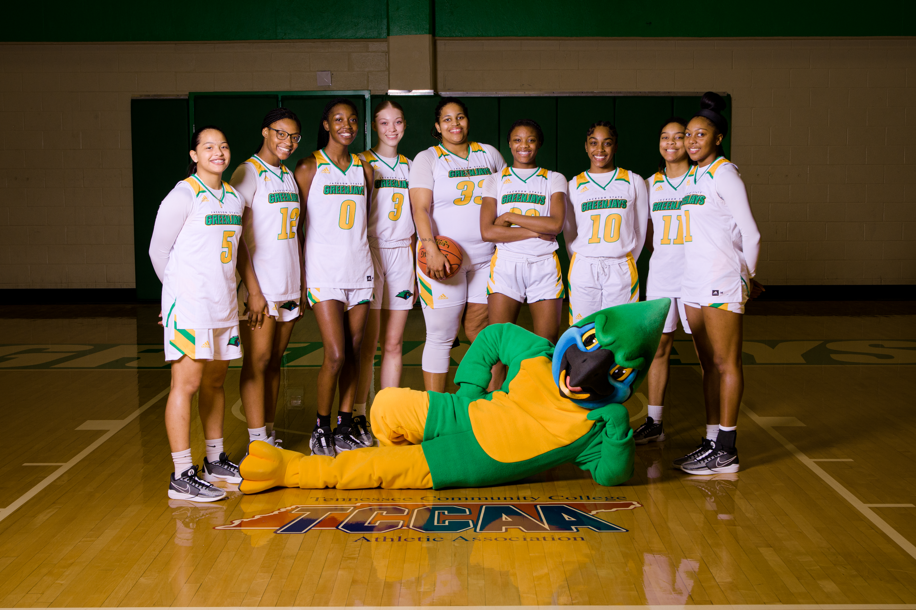 Women's Basketball team photographed with the mascot posed on the gymnasium floor.